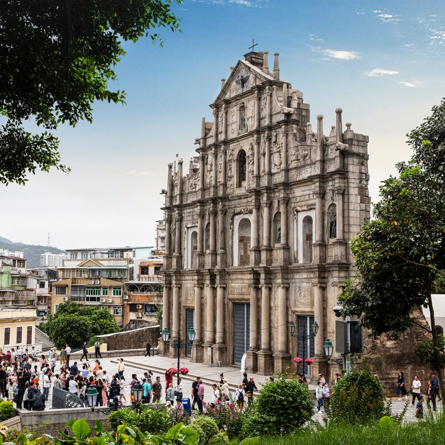 The facade of the Ruins of St Pauls stands tall as people gather beneath to admire it. 