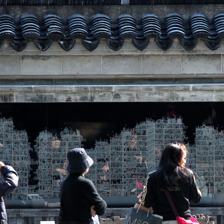 People go sightseeing at Kowloon Walled City Park and gather around a mural depicting the Kowloon Walled City.