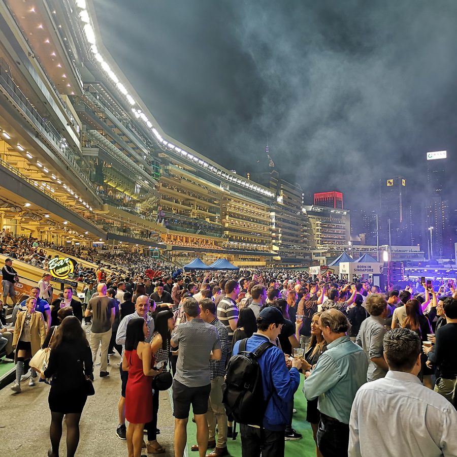 Crowds of people spectate the horse races at Hong Kong Jockey Club during Happy Wednesday.