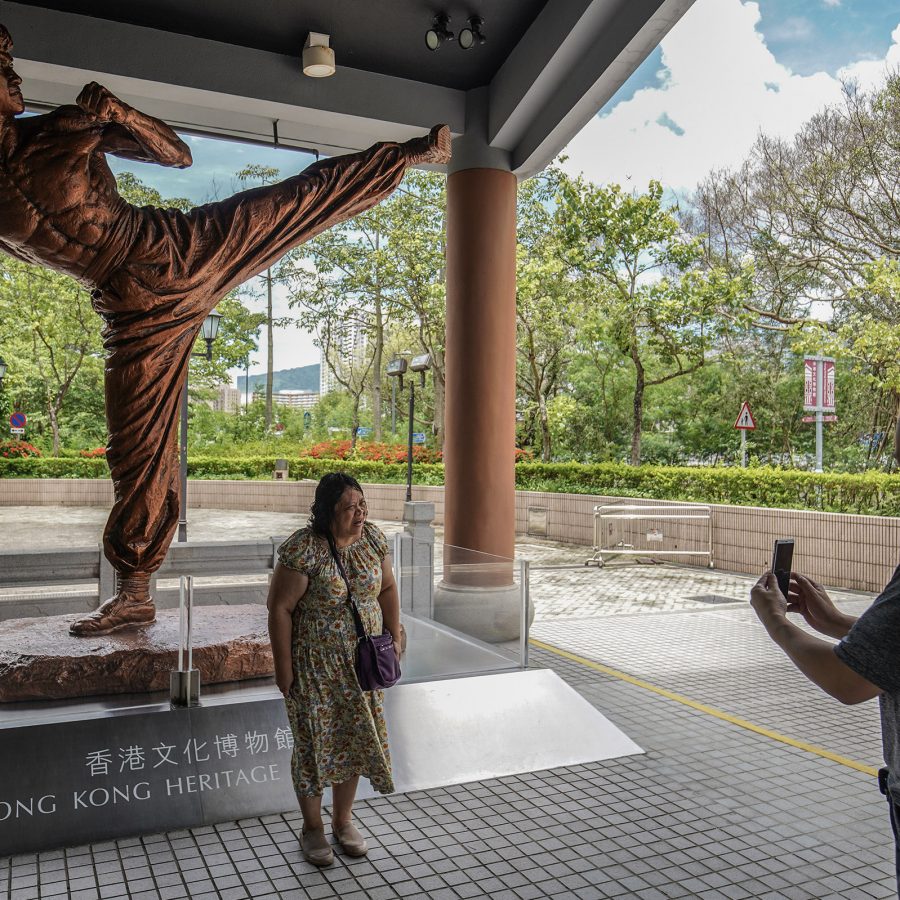 A person poses in front of a statue of Bruce Lee at an exhibit at the Hong Kong Heritage Museum.
