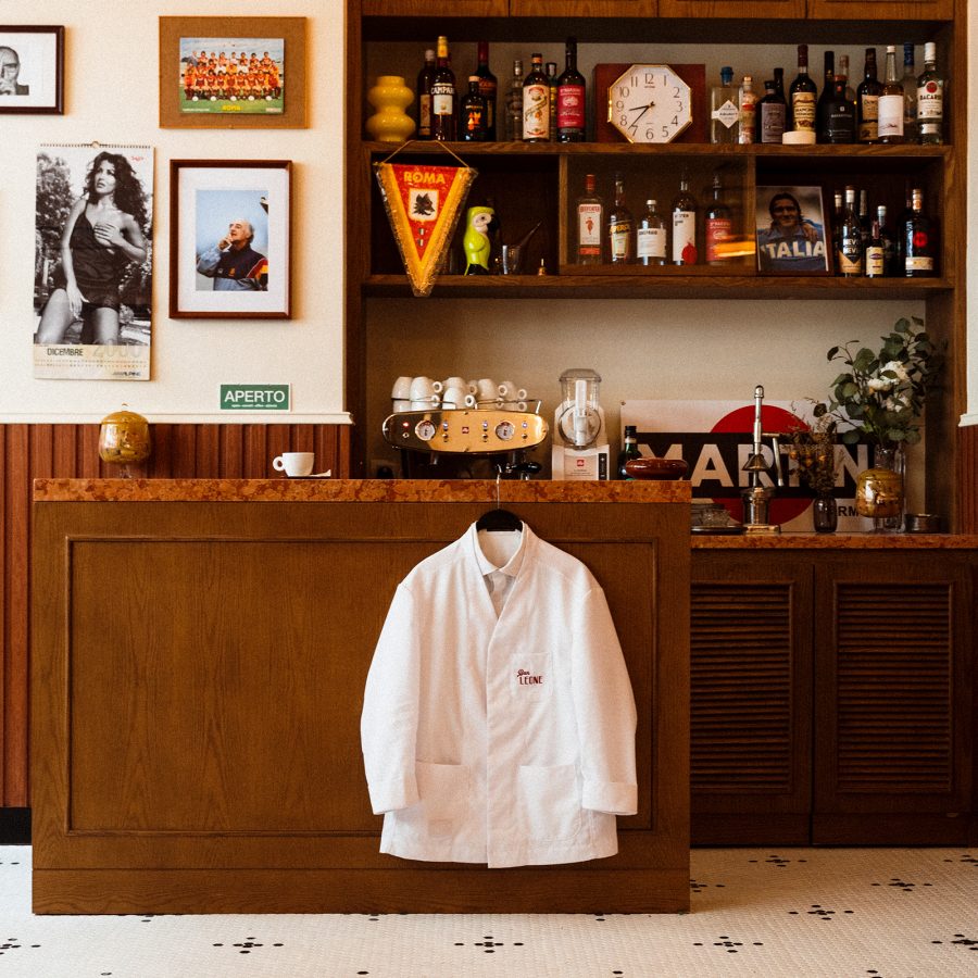 The reception of Bar Leone shows a shelf of liquor next to a wall of framed images.