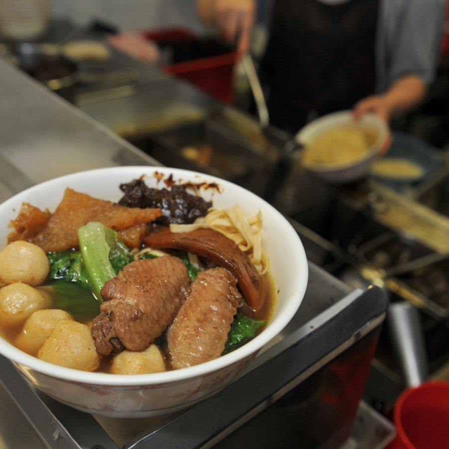 A large bowl of cart noodles includes fish balls, marinated chicken wings and noodles.
