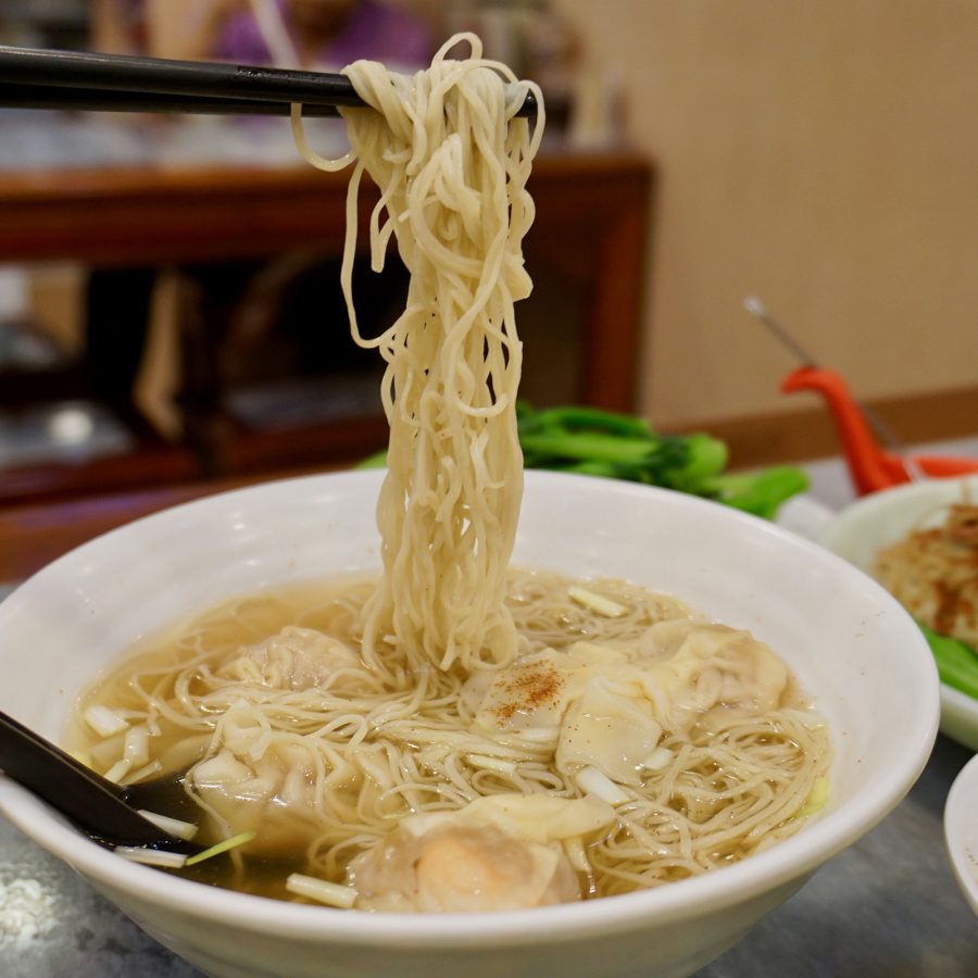 A bowl of wonton noodles features wavy thin noodles and large juicy wonton.