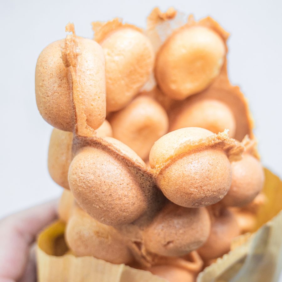 A person holds a bag of egg waffles. 