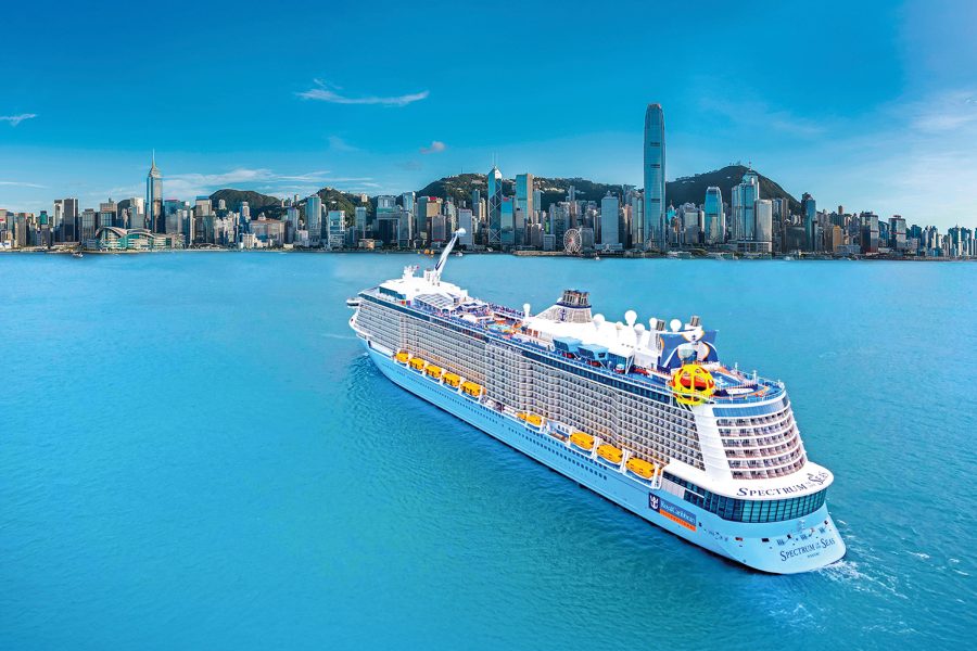 Royal Caribbean’s Spectrum of the Seas cruise ship in the water with Hong Kong’s skyline in the background.