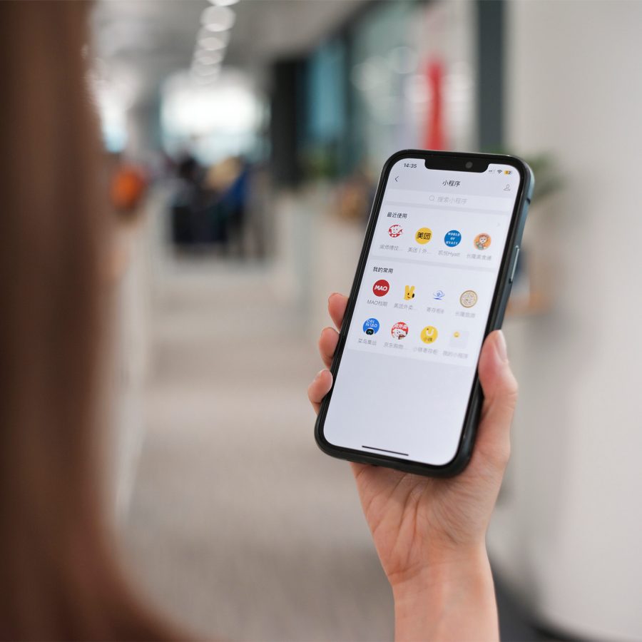 A woman holds up her smartphone with the WeChat app open.