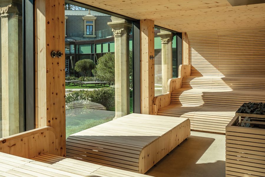 The interior of a sauna room at De Montel – Terme Milano has a glass floor-to-ceiling window looking out at the courtyard.