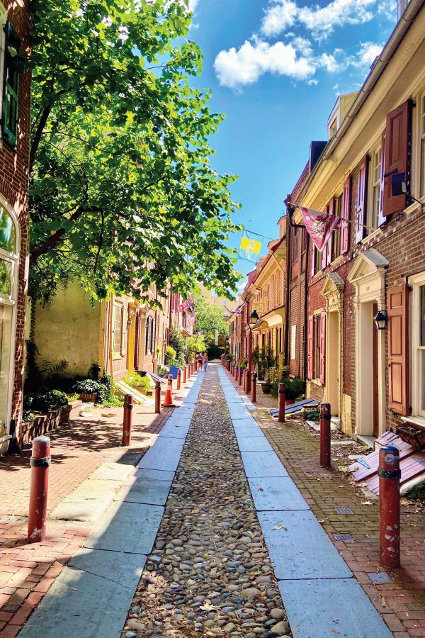 an exterior view looking down Elfreth’s Alley, with red-brick buildings and red bollards to the left and right