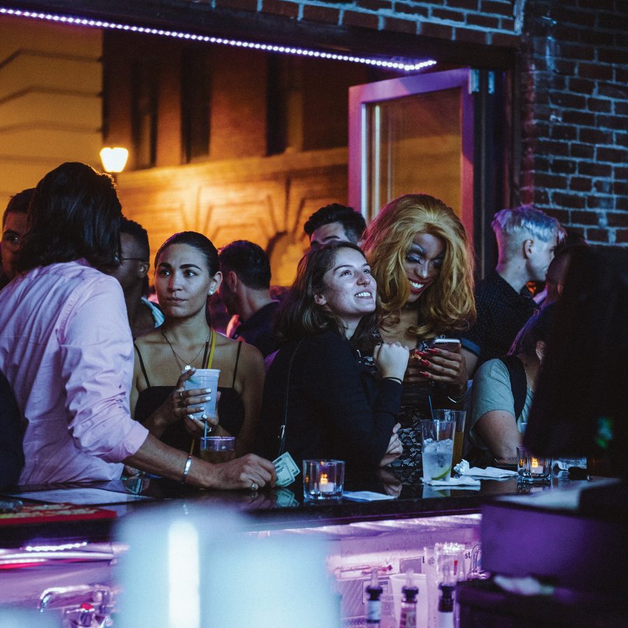 Interior view of people standing at the bar of Woody’s Bar.