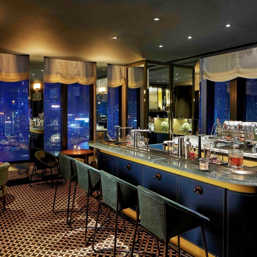 The bar and lounge area at Manor Club of Rosewood Hong Kong at night, offering a wide range of cocktails and beverages against the backdrop of Victoria Harbour.