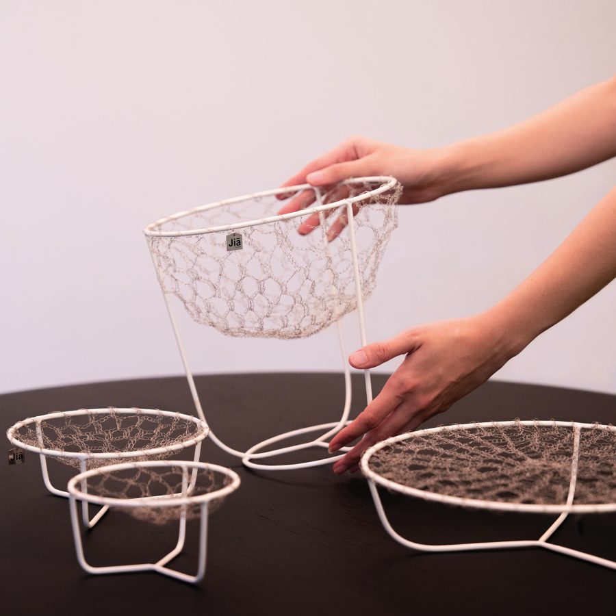 A pair of hands arrange homeware designed for storage and decoration on top of a surface at Jia Collective