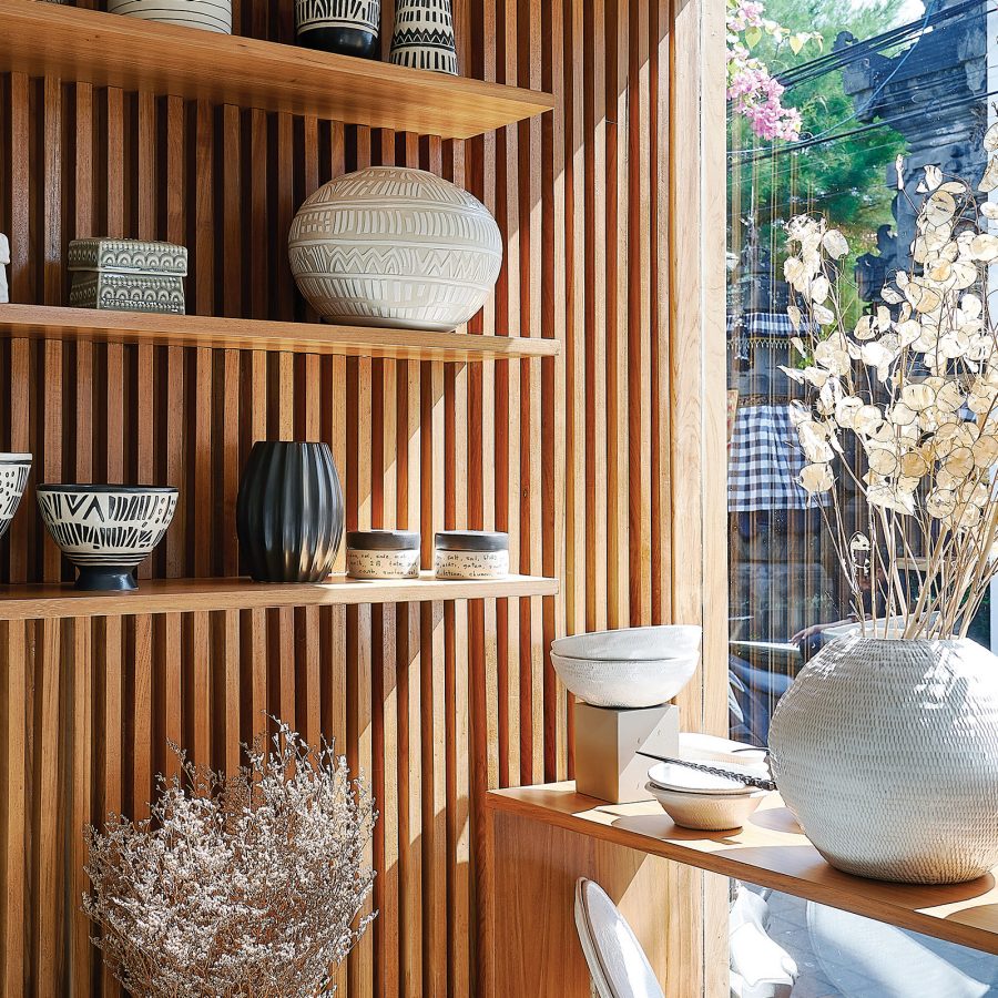 Ceramic bowls and ornaments are on display on wooden shelves at Kevala, Bali.