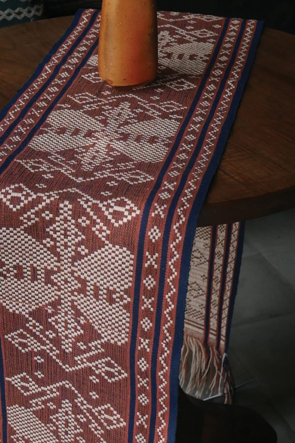 A cloth with a stitched pattern is displayed at Threads of Life.