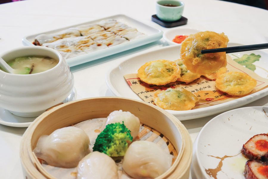 A close-up view of someone using chopsticks to pick up puff pockets, with other dishes in the foreground