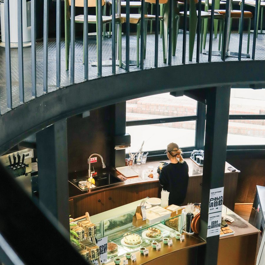 Interior view of Ginger Coffee, with a woman behind the counter and cakes in a cabinet.