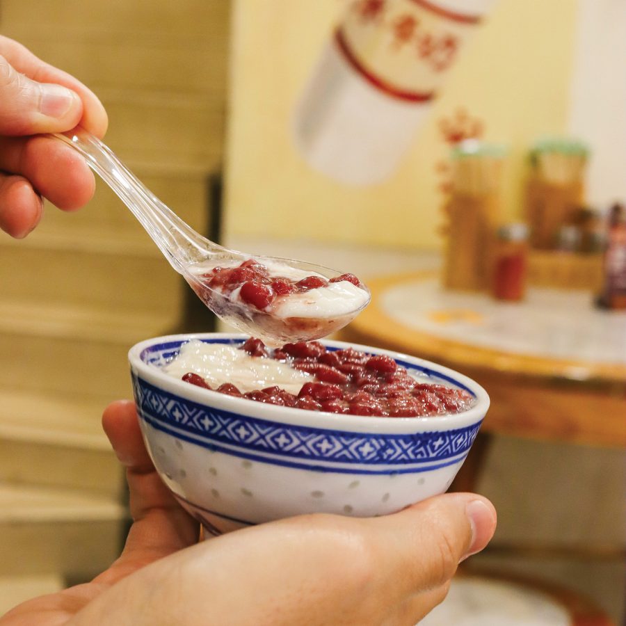 A close-up view of a person with a spoonful of red-bean dessert. 