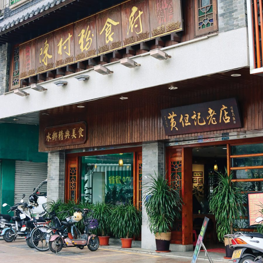 Exterior view of Wong Dan kee Chencunfen restaurant with plants and motorbikes outside the entrance.