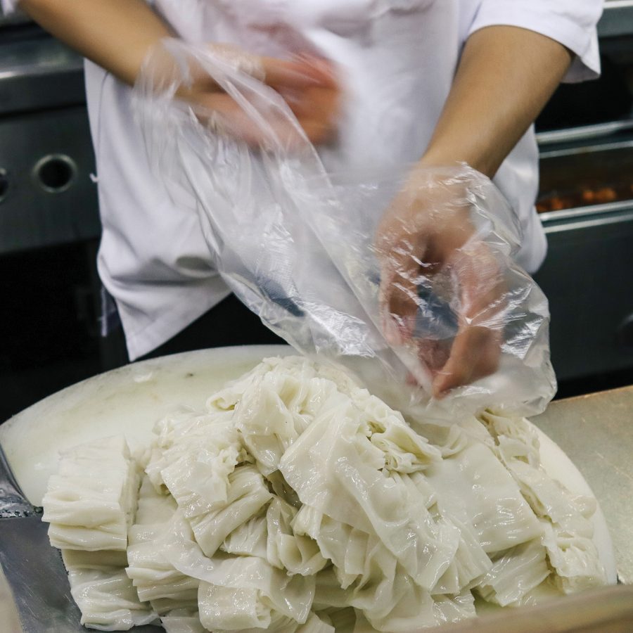 A chef prepares fresh noodles in a kitchen.  