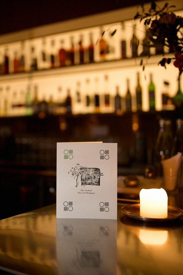 Closeup of a name card and logo of Bar Blanc bar in Shanghai with a view of the bar in the backdrop. 