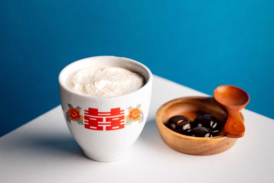 Closeup of a white creamy cocktail in white ceramic cup with black perals on the side, served at Epic bar in Shanghai.