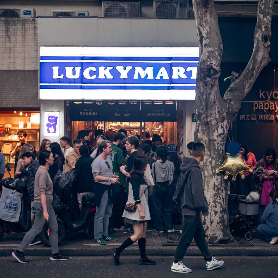 A street view of Lucky Mart in Shanghai with a crowd of people walking past. 