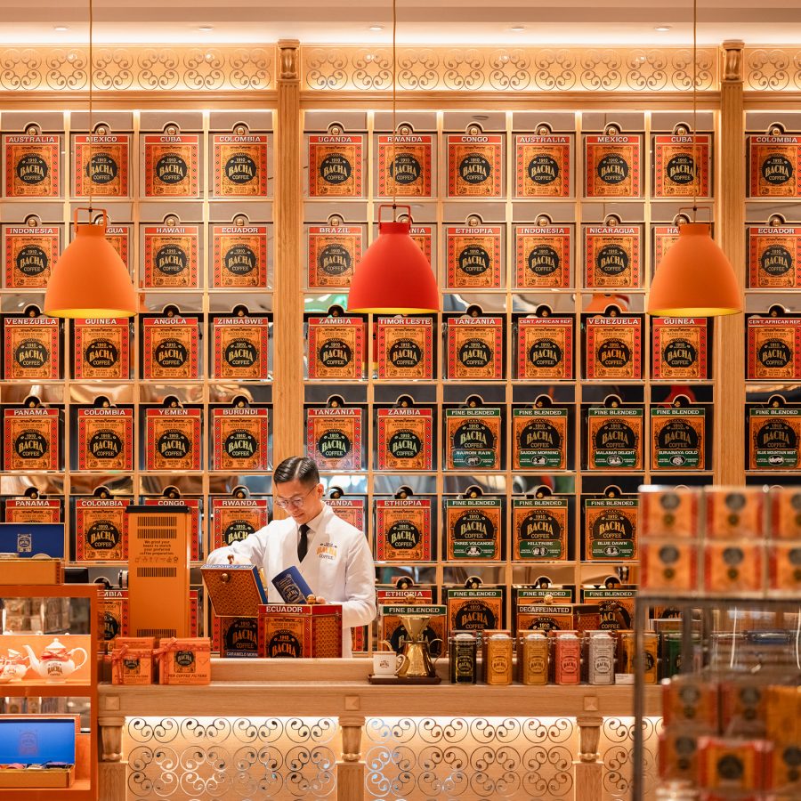 A man stands in front of a wall covered in large copper tins as he works at Bacha Coffee Room in Hong Kong.