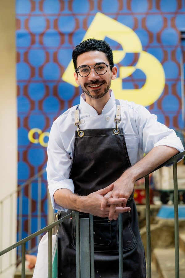 Chef Gabriele Fusi of Primo Posto Restoro smiles as he poses on a staircasel. 