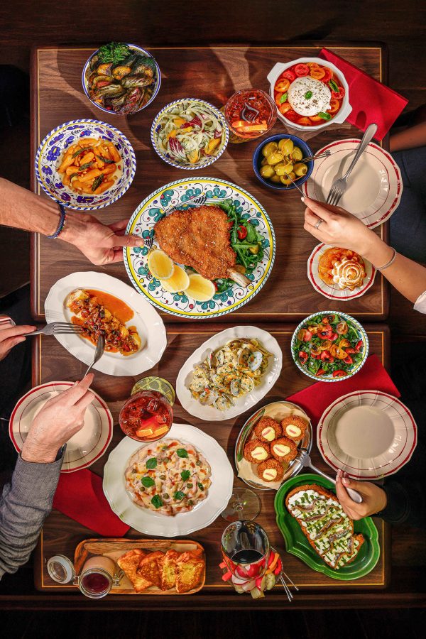 People dig into a table covered in dishes at Primo Posto Ristoro.