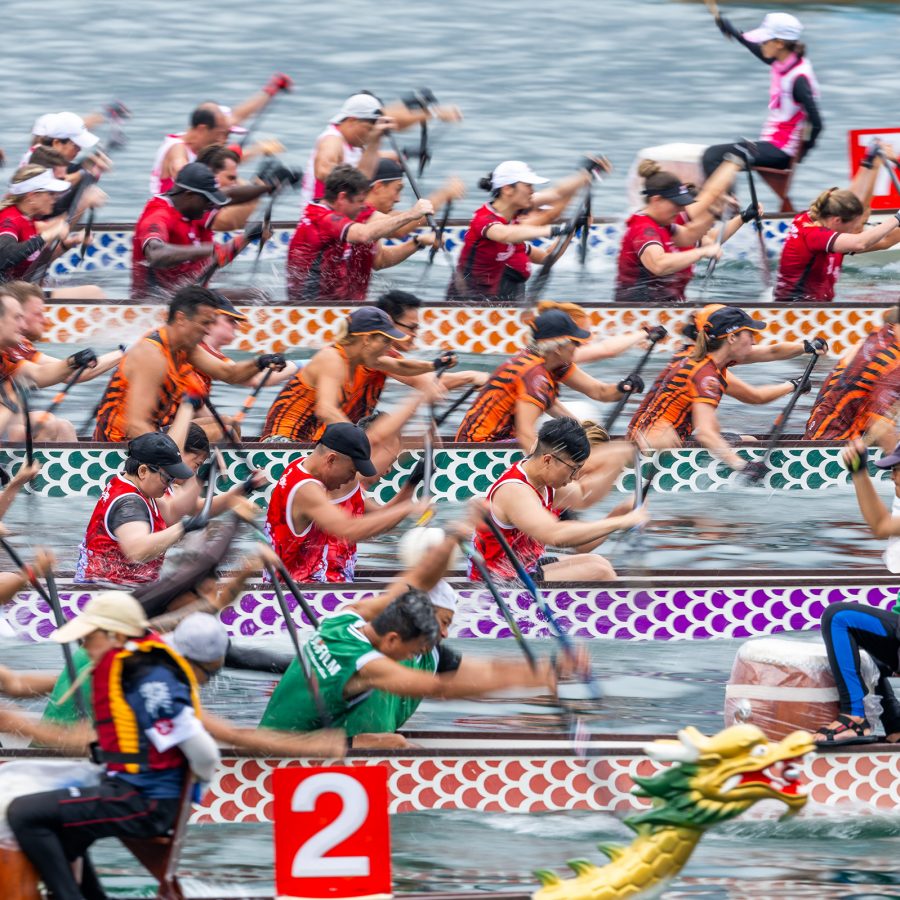Dragon boats race against one another in a row.