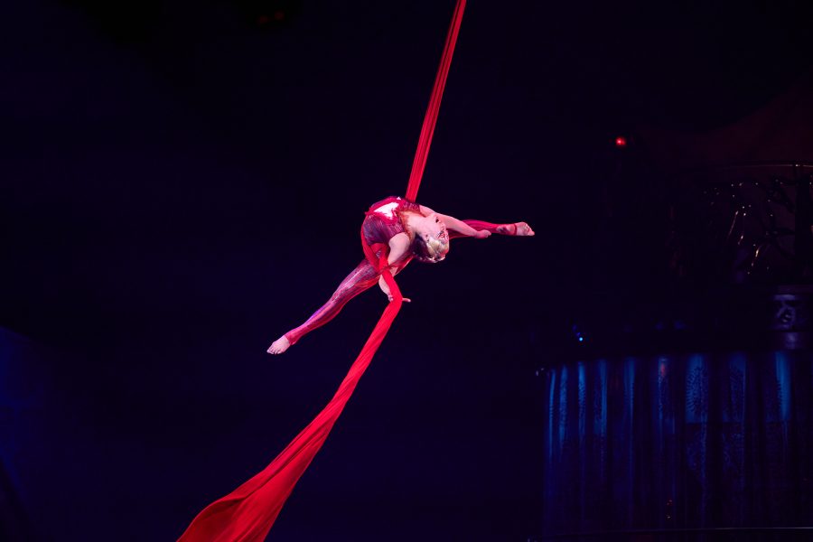 Performer on a red silk rope swings around during Kooza.