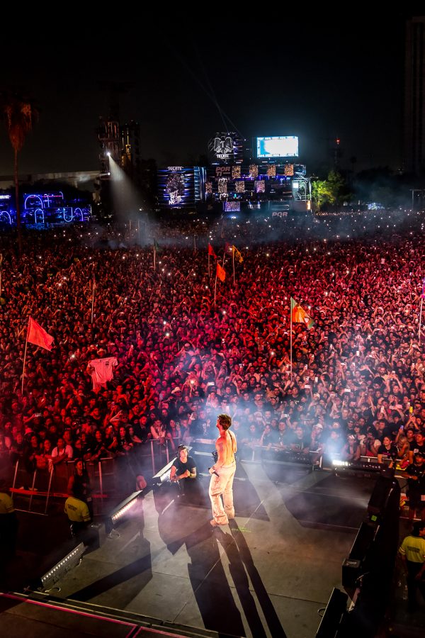 The Chainsmokers perform on stage in front of a packed audience at an outdoor concert venue. 