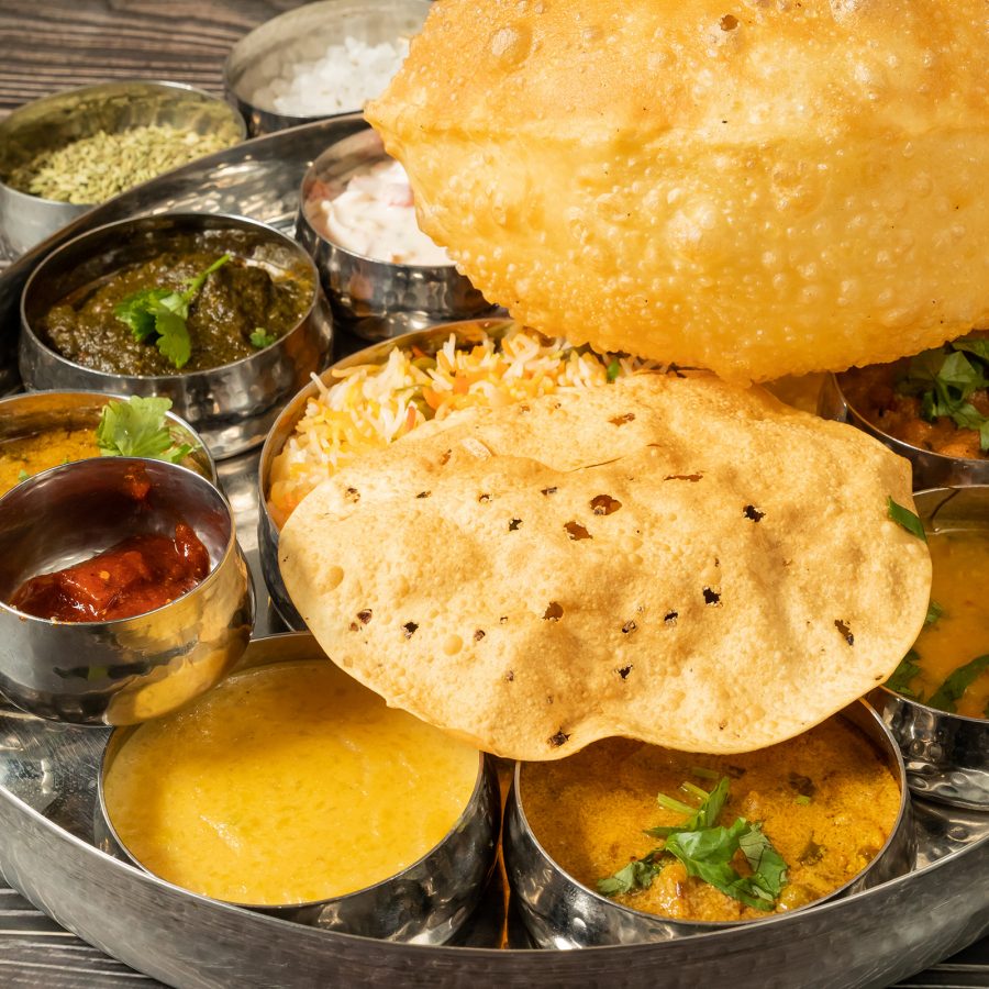 A closeup of a plate of thali, filled with various curries, sauces, papadum and puri served at Woodlands.