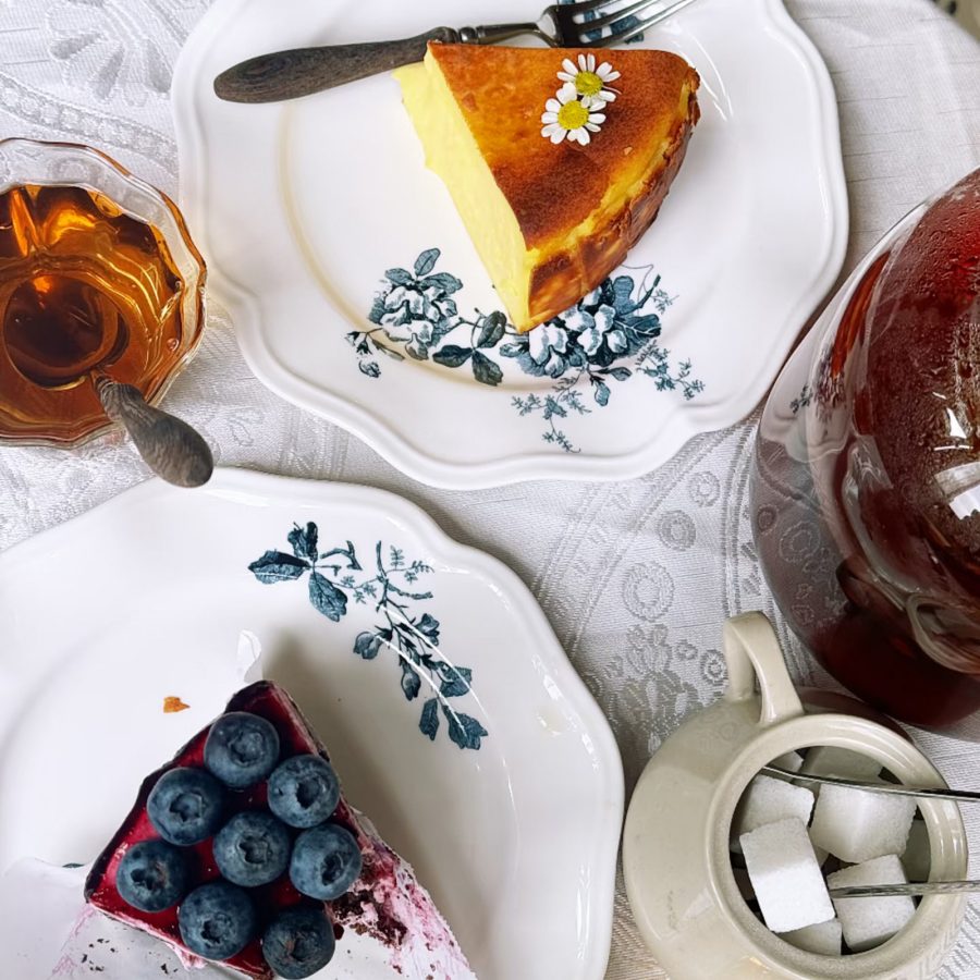 Plates holding various desserts like cake slices and teacups cover a table.