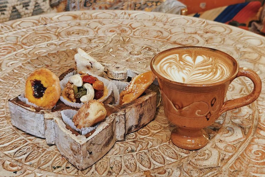 Desserts featuring naipizi and a latte are arranged on an intricate table. 