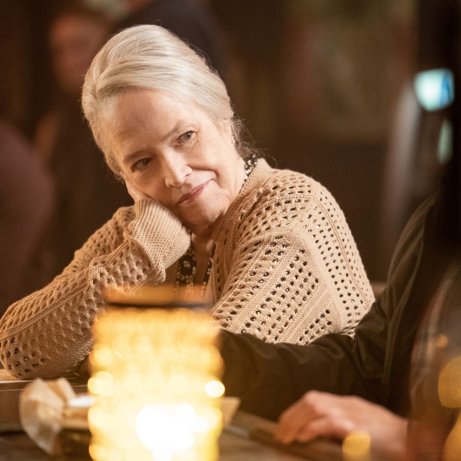 In a scene from Matlock, older lawyer Matty (Kathy Bates) sits alone at a bar, dressed in a cardigan and looking thoughtful. 