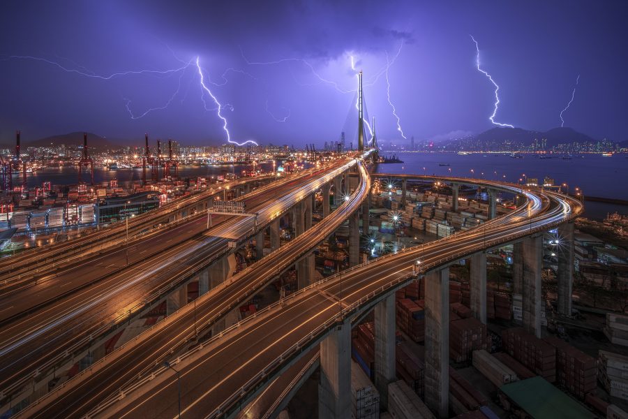 Lightning cracking overhead as cars zoom past on raised Hong Kong highways.