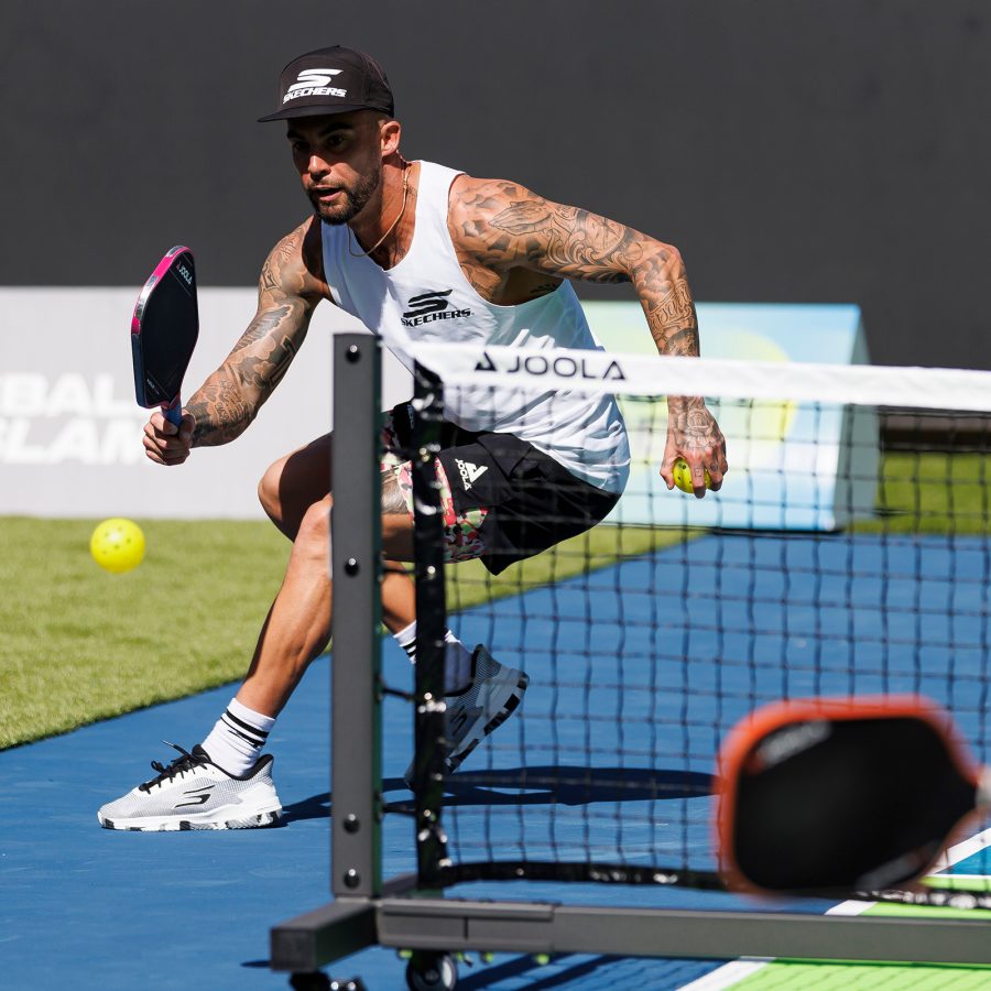 A male pickleball player returns a ball during a pickleball game. 