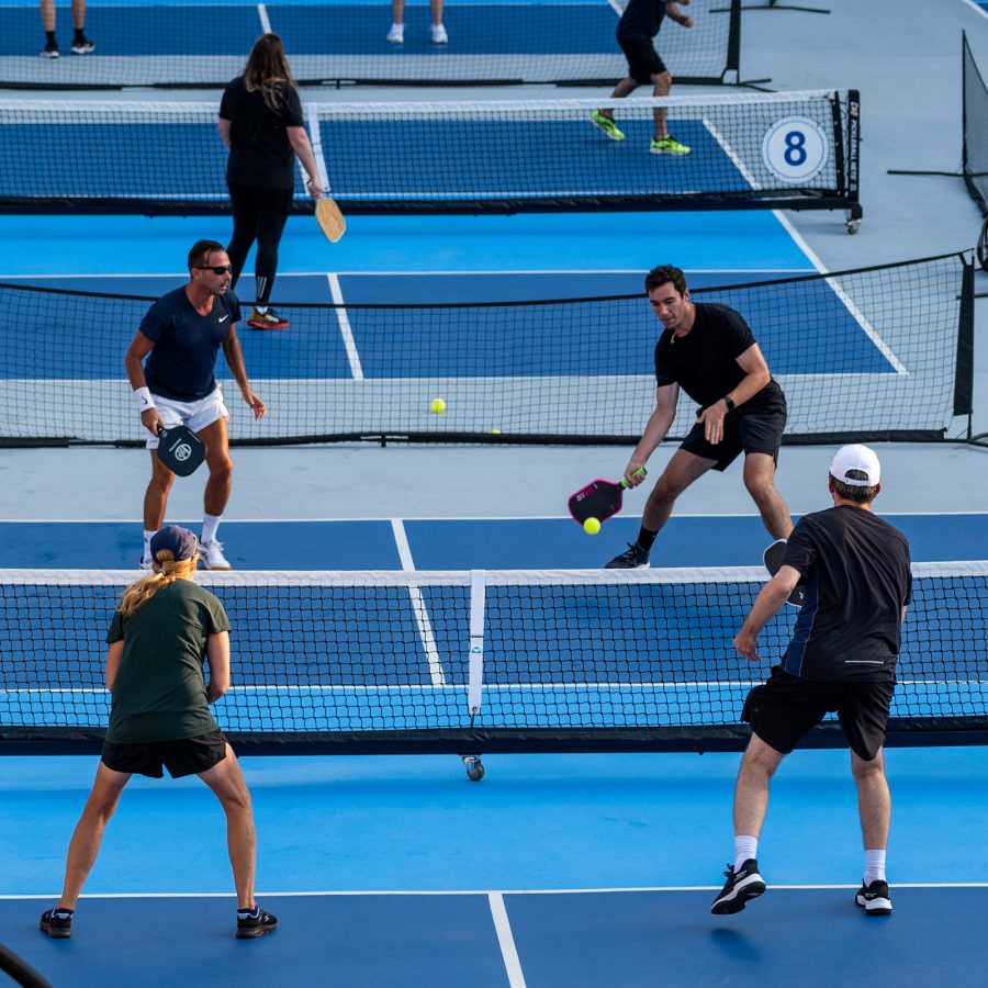 Four pickleball players are in the middle of a rally. 