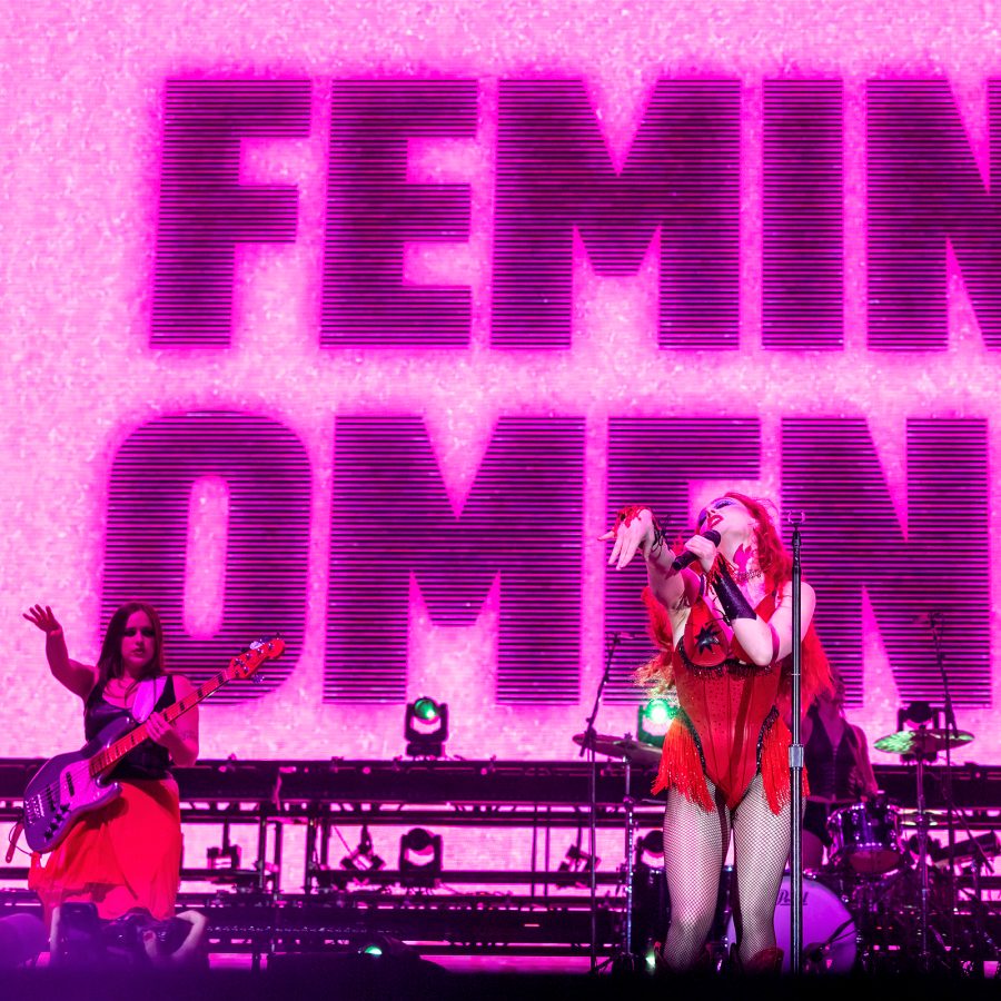Chappell Roan dancing in a red dress against a backdrop that reads ‘Feminiomeno’.  