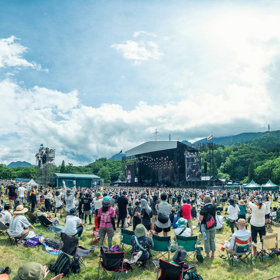 Festival goers sit in a green field as they watch the stage at Fuji Rock Festival.