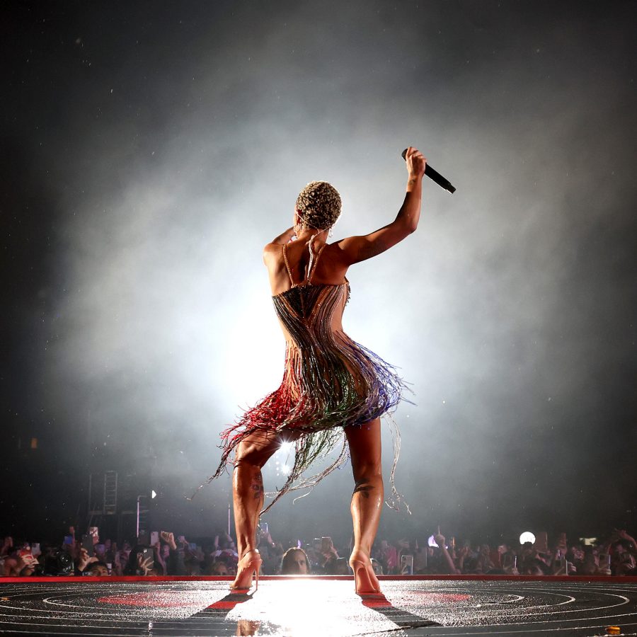 A woman dances for a crowd against a white light onstage.