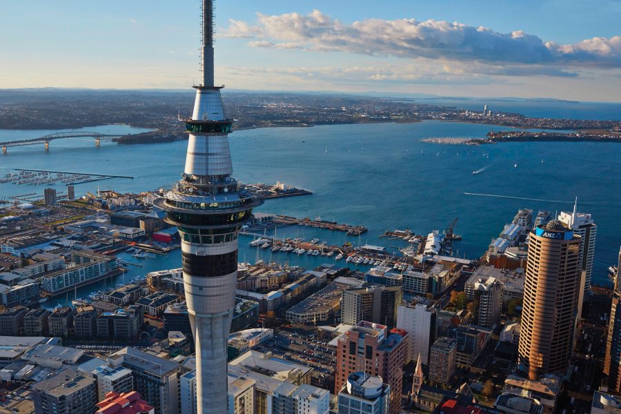Aerial exterior view of Auckland CBD, with the Sky Tower in the foreground and the bridge and Devonport in the background.