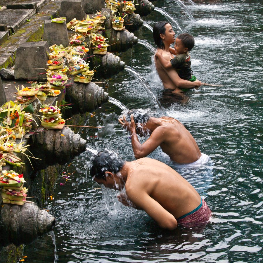 People bathe in streams of water at an outdoor pool.  