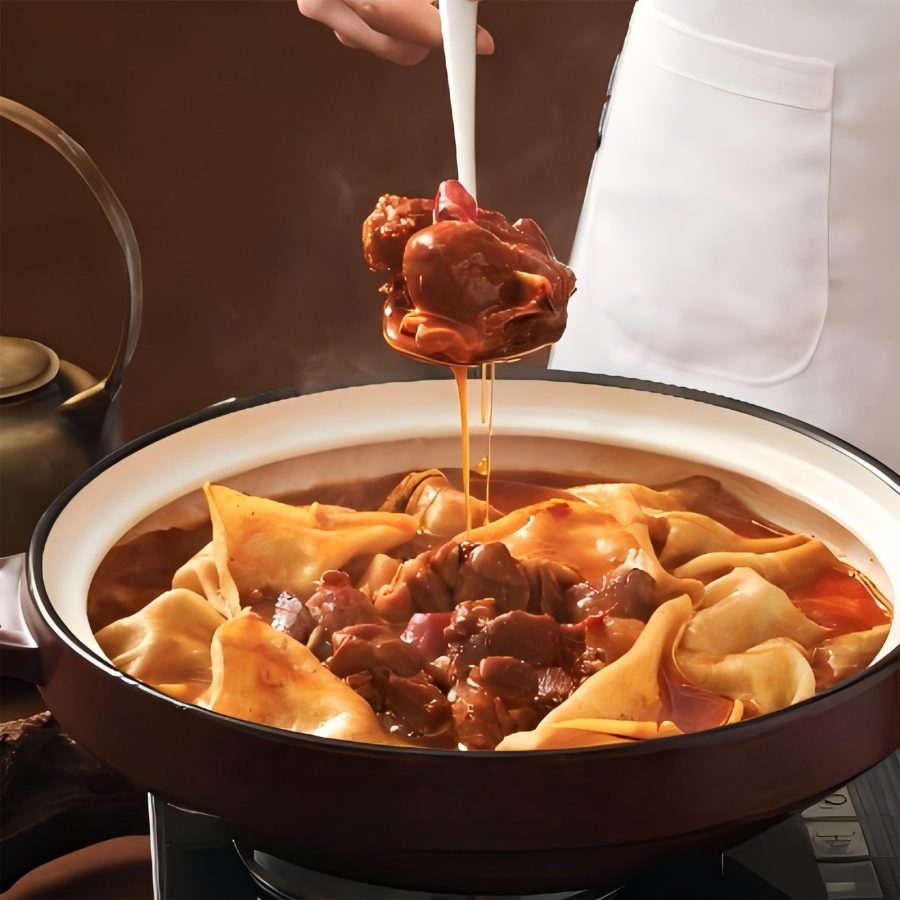 A hand holding a spoon over a bowl of food from SP Chain Catering. 