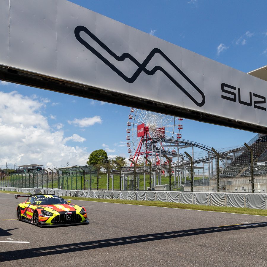 A red and yellow striped car lines up at the starting line of the Suzuka Circuit with a Ferris Wheel in the background.