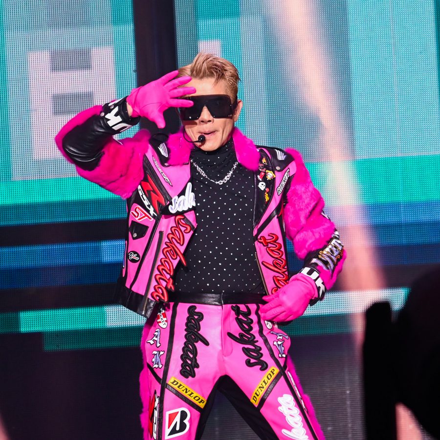Singer Aaron Kwok performs on stage in a hot pink outfit.