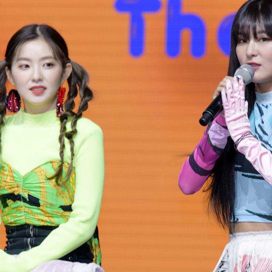 Red Velvet members Irene and Seulgi sit and talk during an event.