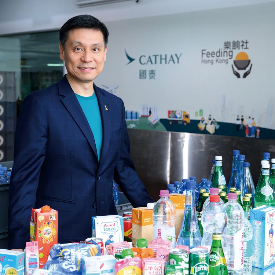 Cathay General Manager Corporate Affairs Andy Wong standing behind a table of packaged beverages collected for Feeding Hong Kong.