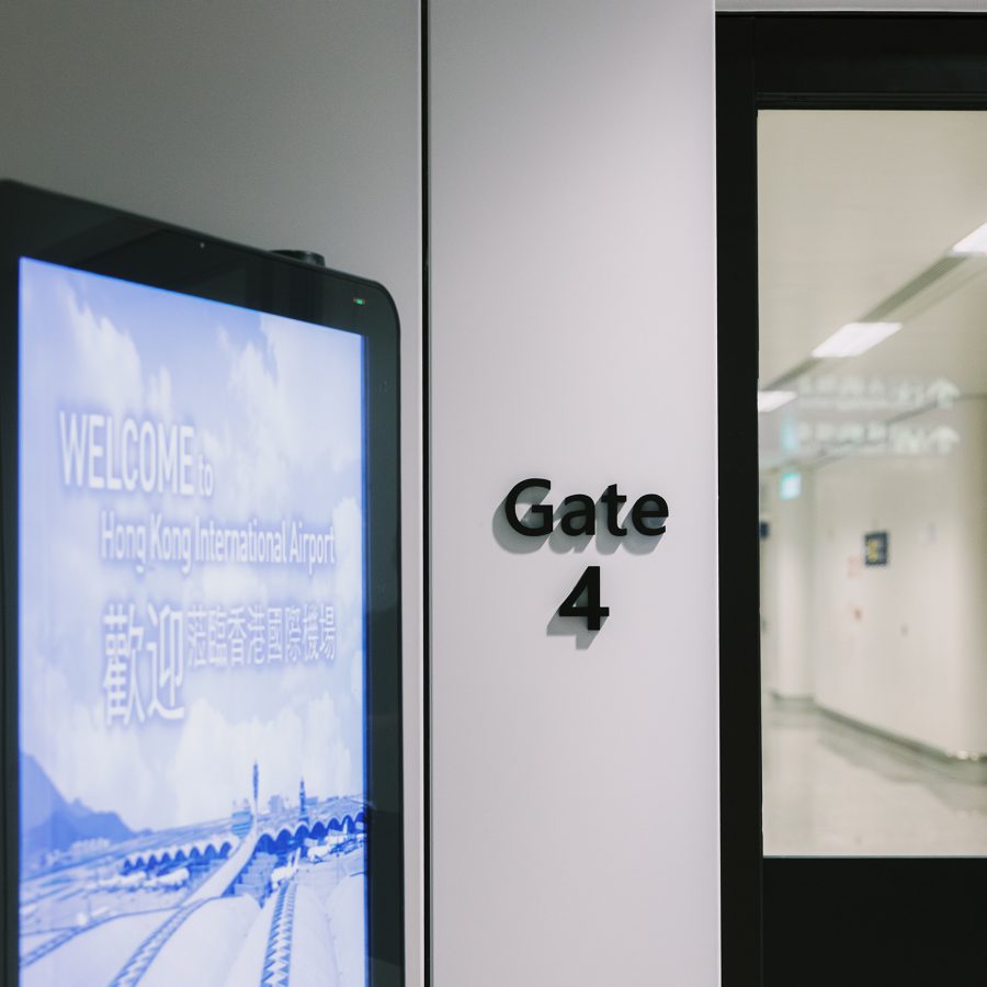  A view of a transfer hallway with an electronic signboard and sign that reads “Gate 4”.