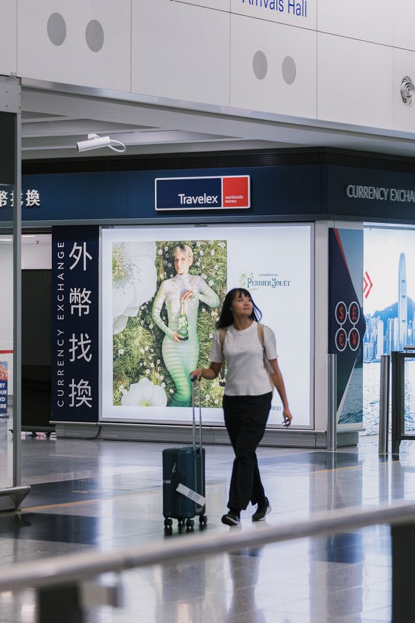 Girl walks through Arrival Hall A at HKIA with luggage in hand.